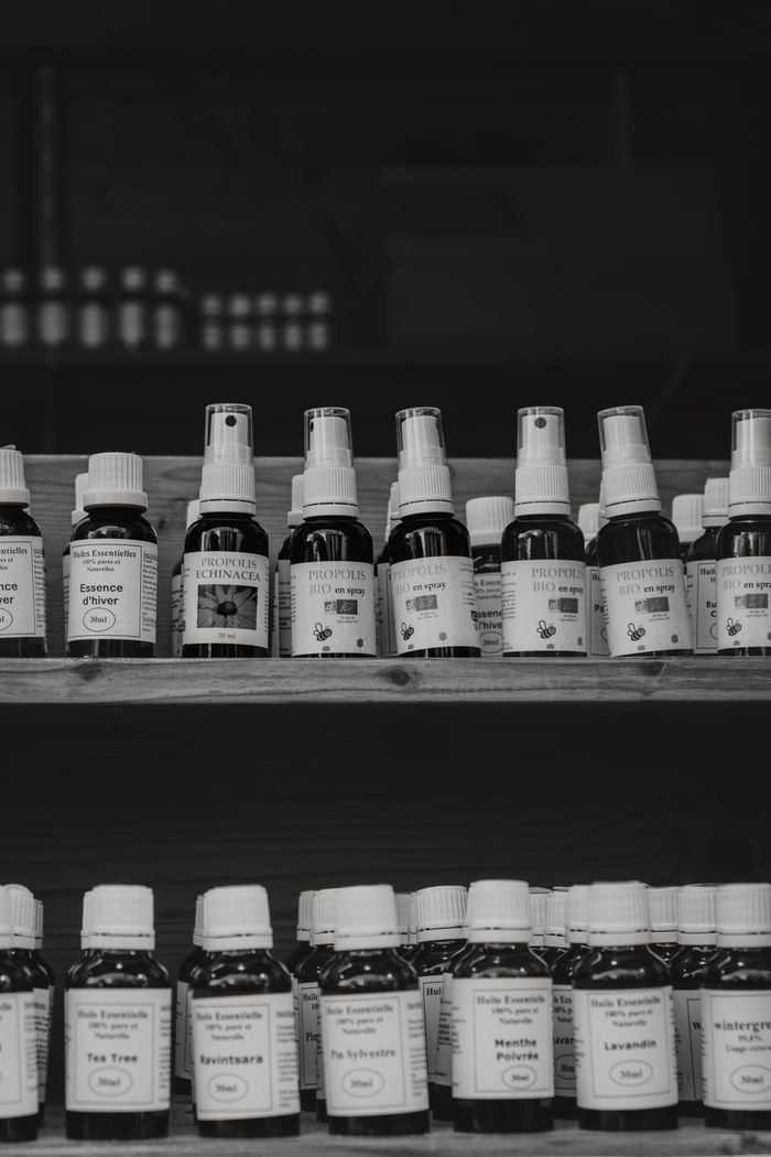 A black and white image of natural health products on wooden shelves at a market.