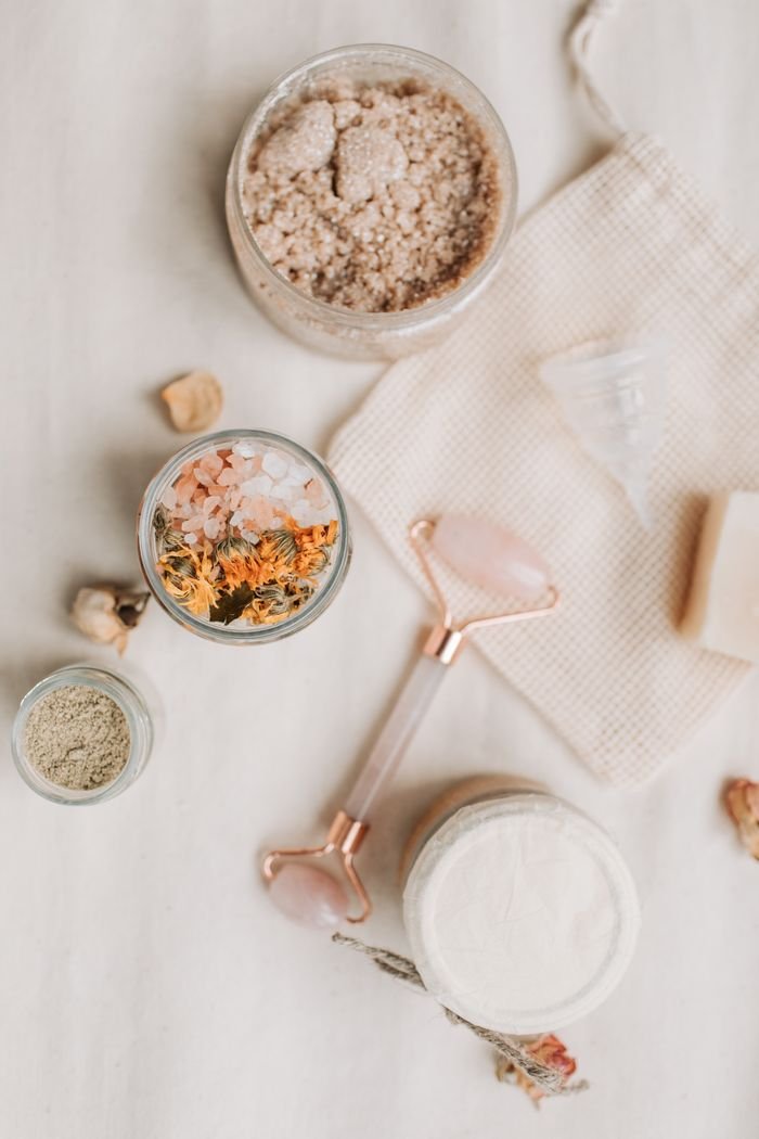 Services Aesthetic flat lay of bath products including a jade roller, bath salts, and natural soaps.